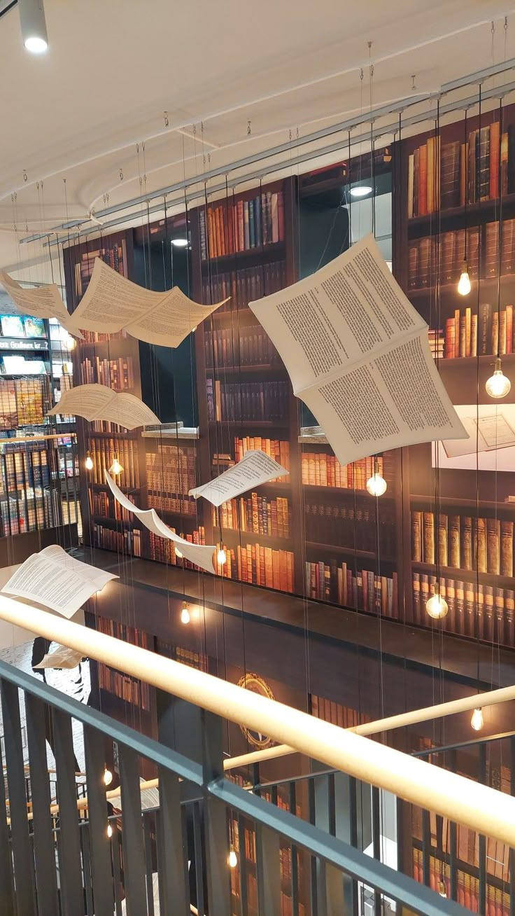 some books are hanging from the ceiling in a room with many bookshelves and lights