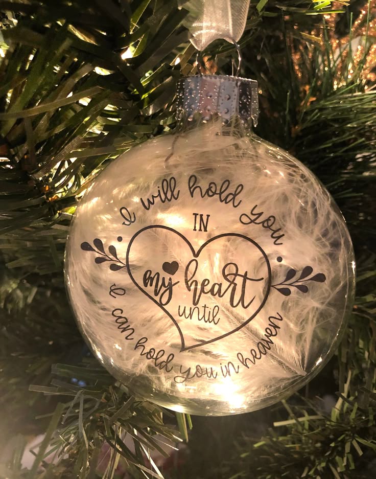 a glass ornament hanging from a christmas tree with the words, we will hold you in my heart