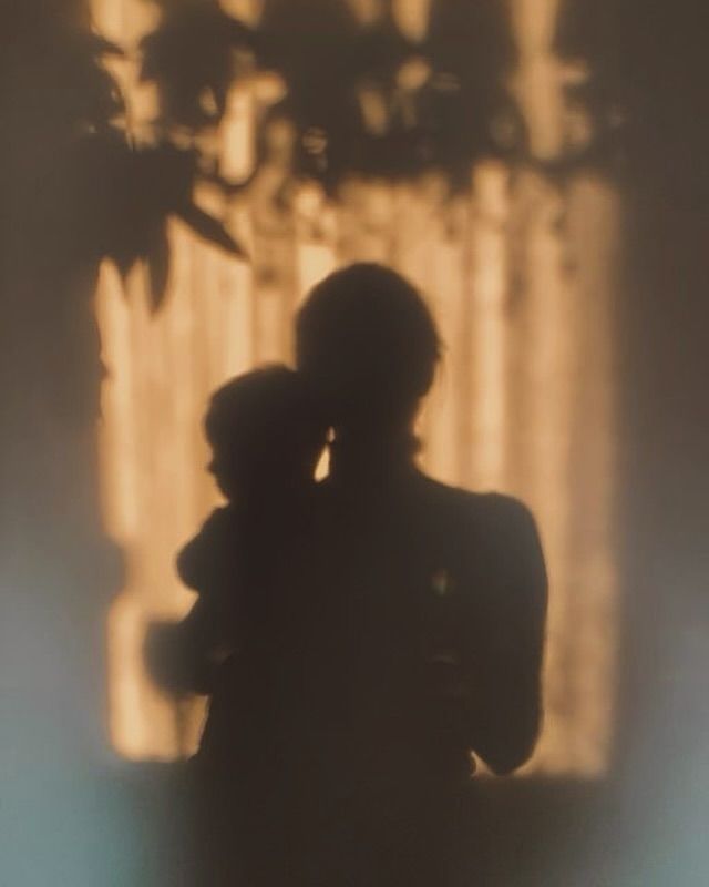 the silhouette of two people embracing in front of a window with light coming through it