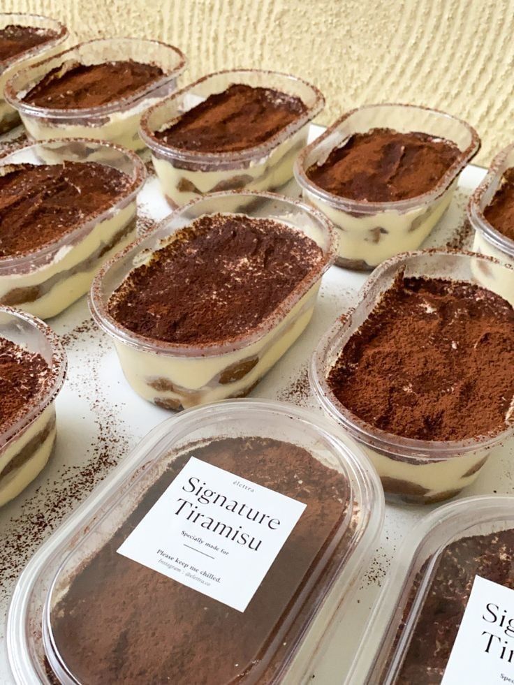 there are many desserts in plastic containers on the table with labels that say signature tirames