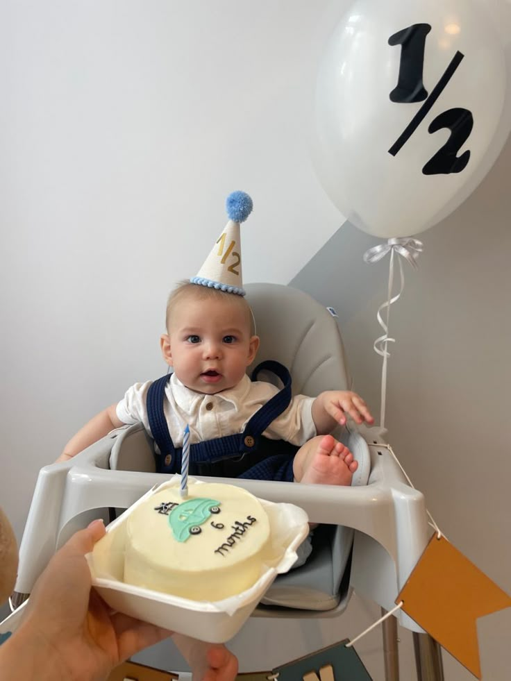 a baby in a high chair with a birthday cake