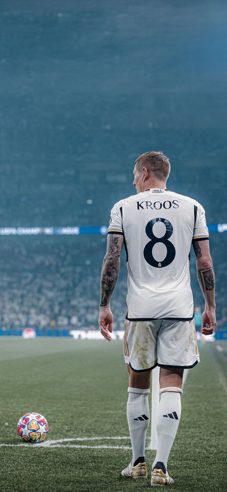 a man with tattoos on his arm standing next to a soccer ball