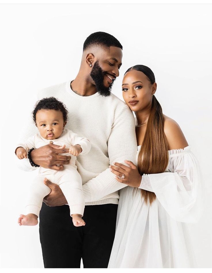 a man and woman holding a baby in front of a white background with the caption's name on it