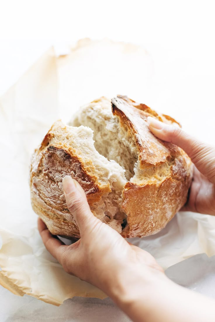 a person holding a piece of bread in their hand on top of some wax paper