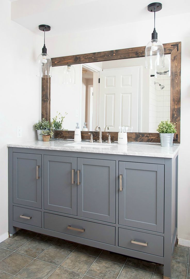 a bathroom vanity with two mirrors and lights above it, along with potted plants on the counter