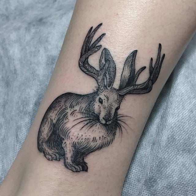 a black and white tattoo of a rabbit with antlers on it's head