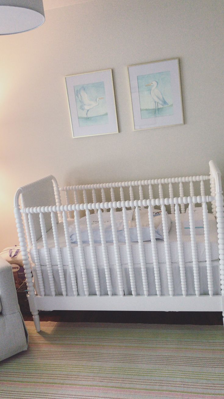 a white crib in a room with two pictures on the wall