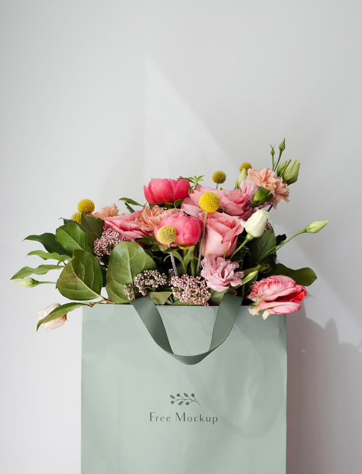 a bouquet of flowers in a green shopping bag