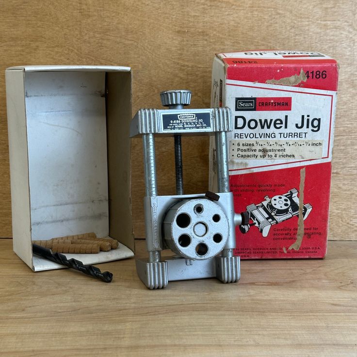 an old metal device sitting on top of a wooden table next to a cardboard box