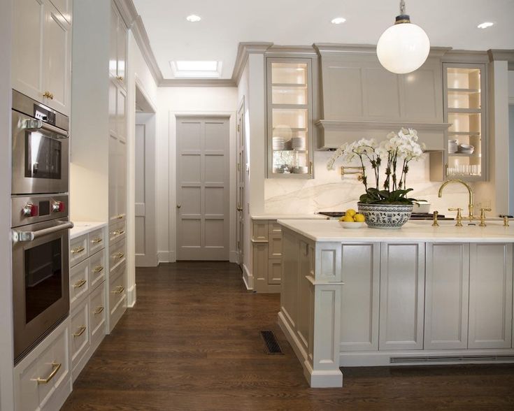 a large kitchen with white cabinets and wood flooring, along with an oven in the center