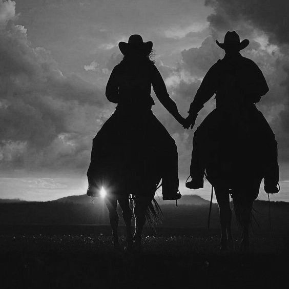 two people riding on the back of horses holding hands