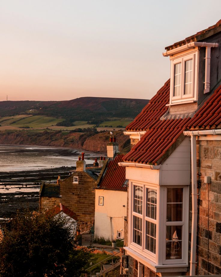 the sun is setting over some houses by the water