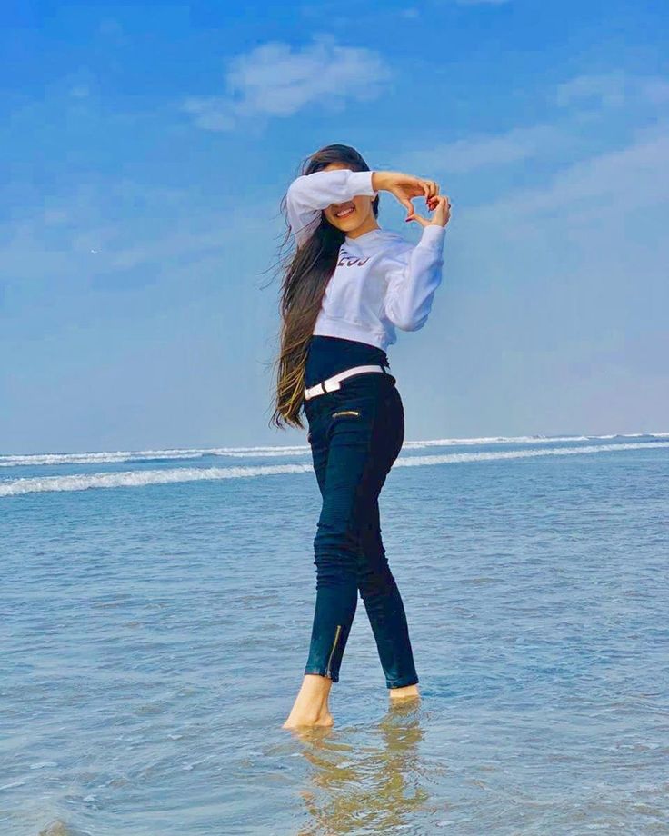 a woman standing in the ocean with her hair blowing back