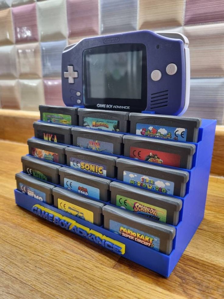 a blue gameboy sitting on top of a stack of games