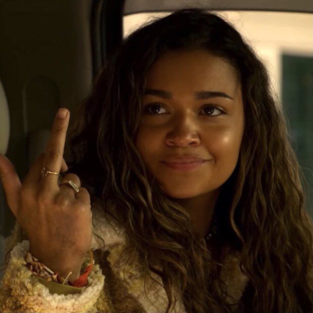 a woman sitting in the back seat of a car holding up a peace sign with her right hand