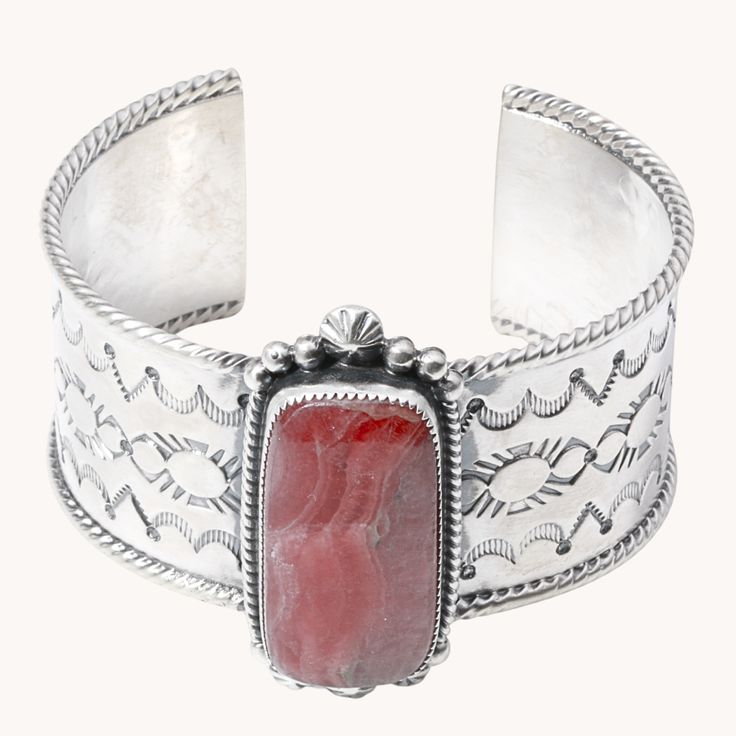 Crafted from sterling silver, this hand-stamped cuff bracelet showcases the stunning beauty of pink rhodochrosite. With its unique variation in color and pattern, this statement piece is a must-have addition to any jewelry collection. Elevate your style with this exquisite and rare accessory. Sterling Silver Cuff Bracelet Rhodochrosite Stone 2" Width Size 7 Artist: P. Secatero for TSkies Hand Stamped Cuff Bracelet, Gallery Jewelry, Pink Rhodochrosite, Wide Cuff Bracelets, Stacked Jewelry, Sterling Silver Cuff Bracelet, Wide Cuff, Men's Jewelry Rings, Sterling Silver Cuff