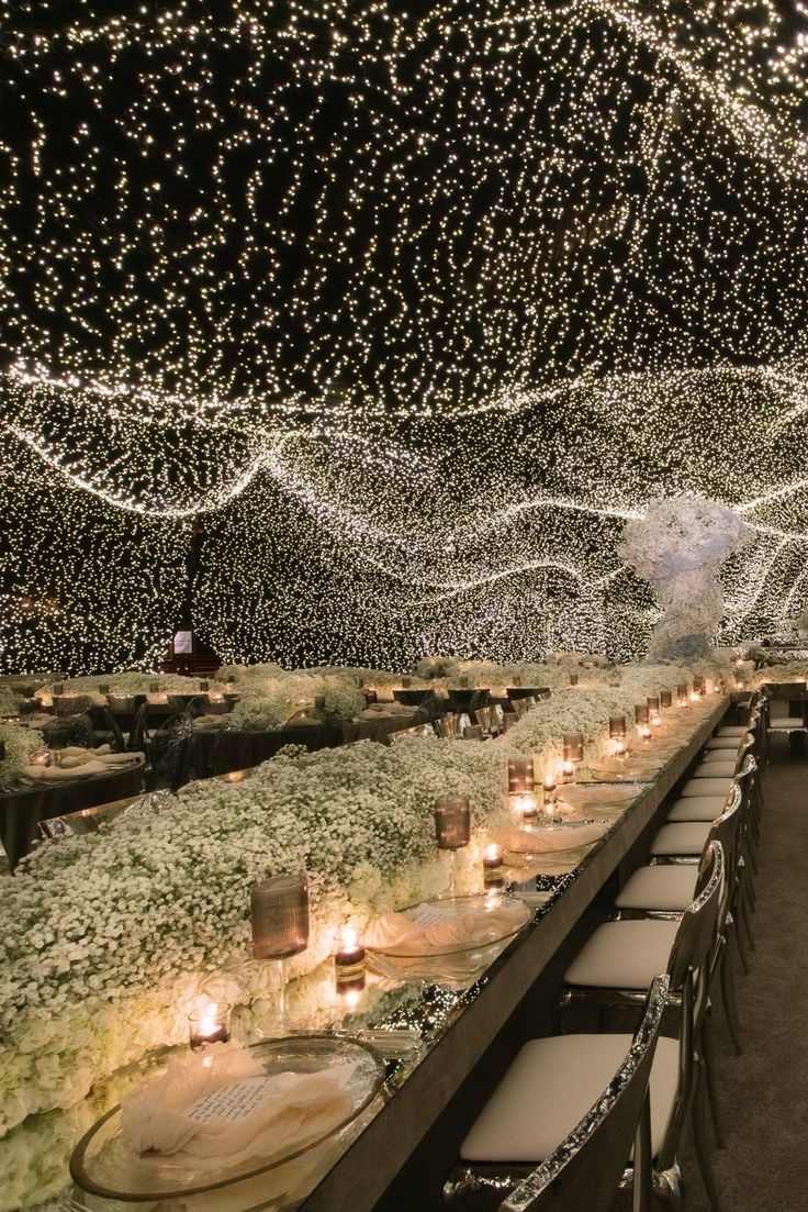 a long table with many candles and lights on the ceiling is set up for an event