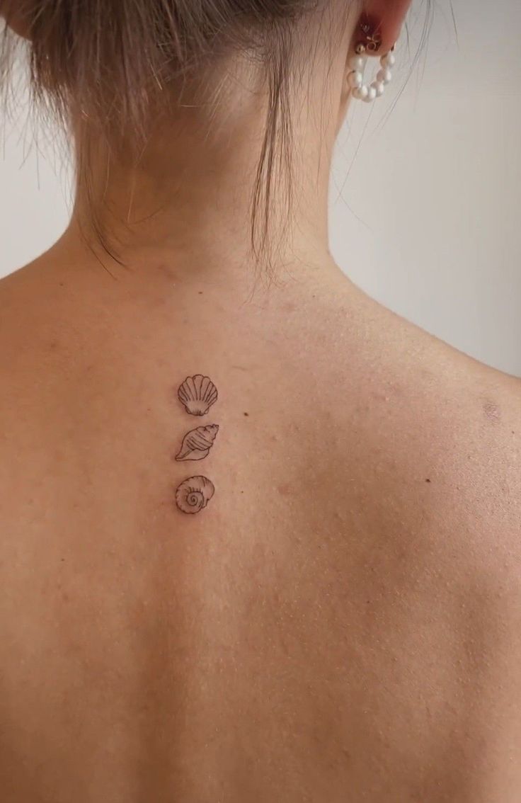 the back of a woman's neck with two seashells tattoo on it