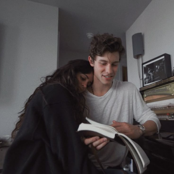 a young man and woman are looking at a book