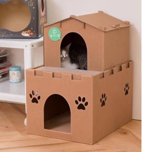 a cat sitting in a cardboard castle with paw prints on the outside and inside it