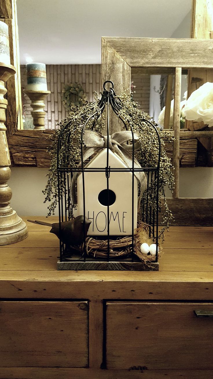 a bird in a cage sitting on top of a wooden table next to a mirror