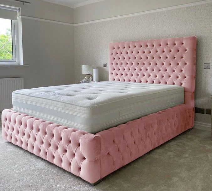 a large pink bed sitting in a bedroom next to a window