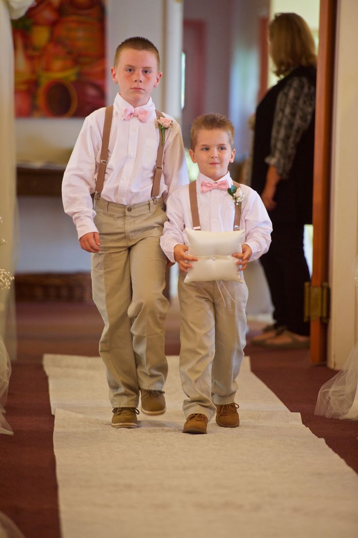 two young boys wearing suspenders and bow ties are walking down the aisle at their wedding