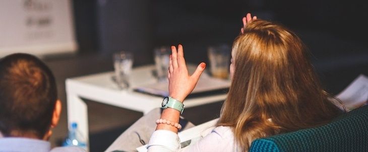 two people sitting in chairs with their hands up