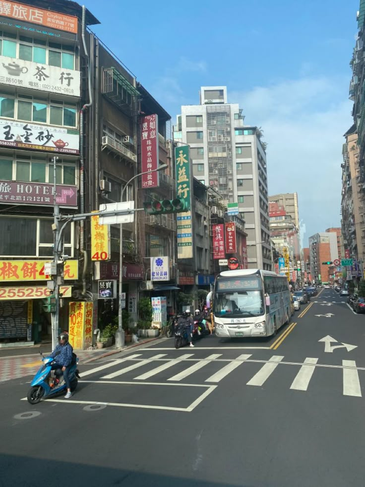 a city street filled with lots of tall buildings and people on motor bikes driving down it