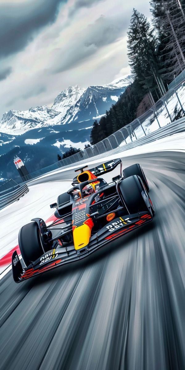 a red and yellow race car driving on a snowy track with mountains in the background