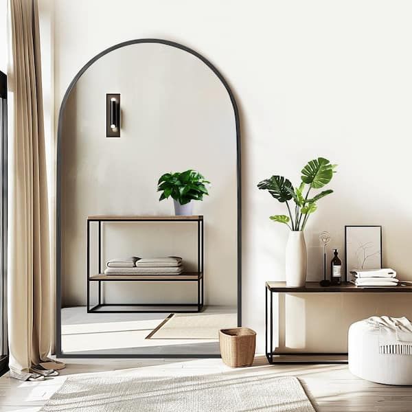 a living room with an arched mirror and two planters on the side of the wall