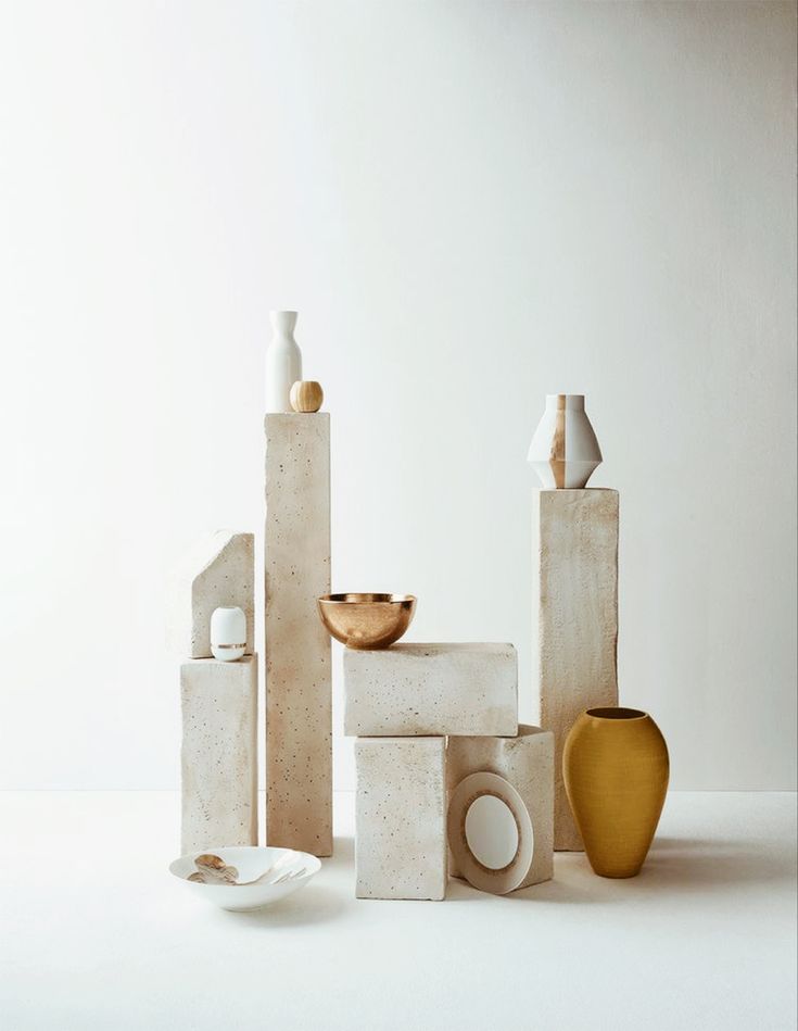 several white and yellow vases sitting next to each other on a table in front of a wall