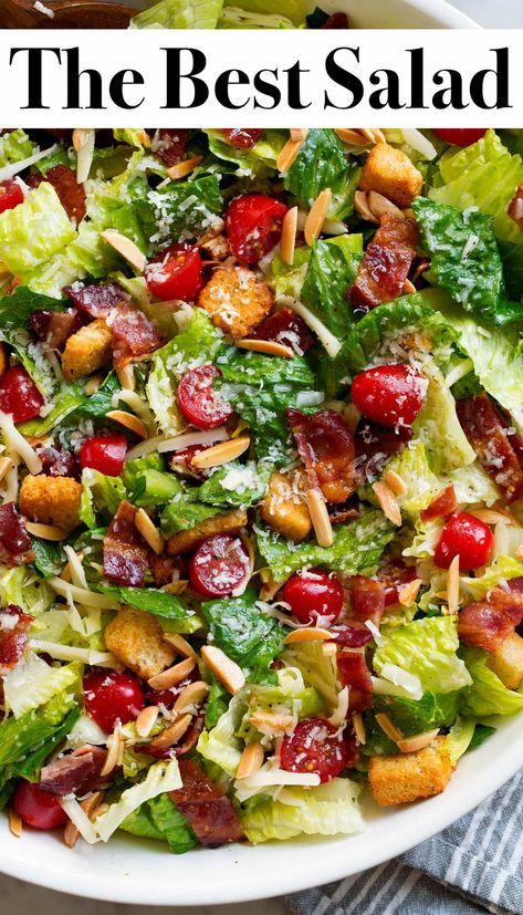 a salad with cranberries, lettuce and almonds in a white bowl