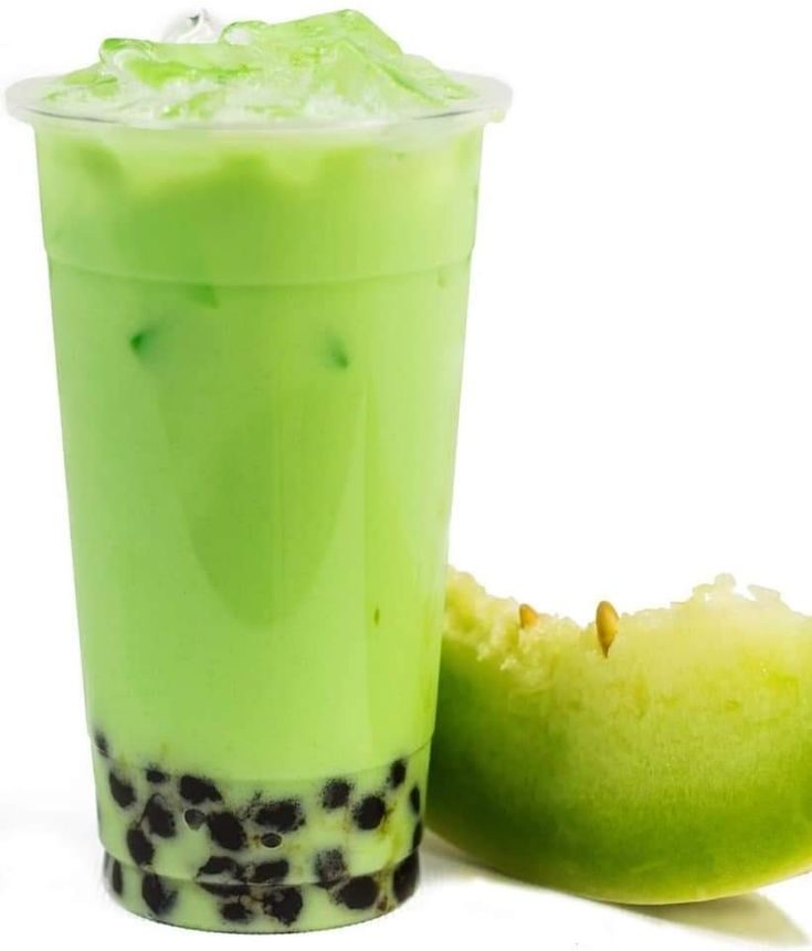 a green drink next to an apple on a white background, with the top half partially eaten