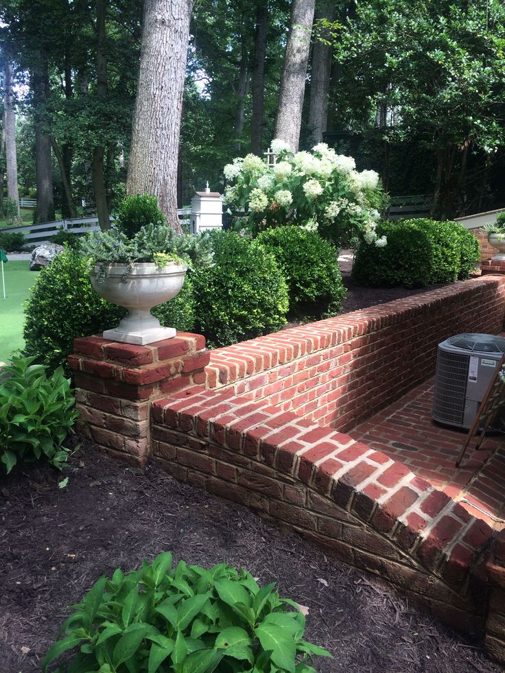 an outdoor garden area with brick steps and potted plants on each side, surrounded by trees