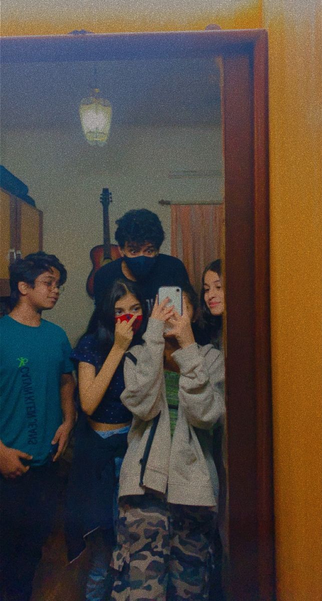 a group of people standing in front of a mirror taking pictures with their cell phones