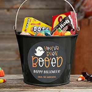 a bucket filled with candy and candies on top of a wooden table