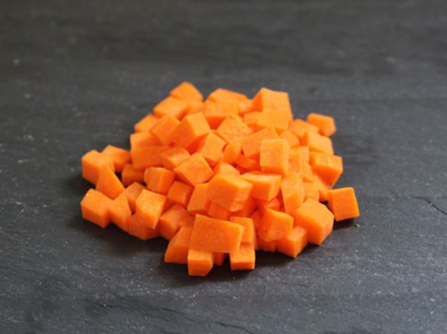 a pile of chopped up carrots sitting on top of a black counter next to a knife