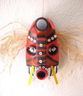 a red and black mask hanging from the side of a wall with eyes on it