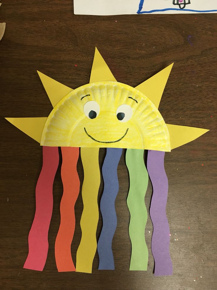 a paper plate that has a sun on it with rainbow streamers hanging from it