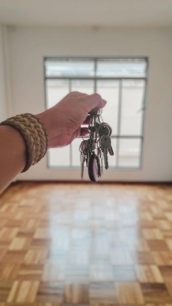 a hand holding keys in front of a window