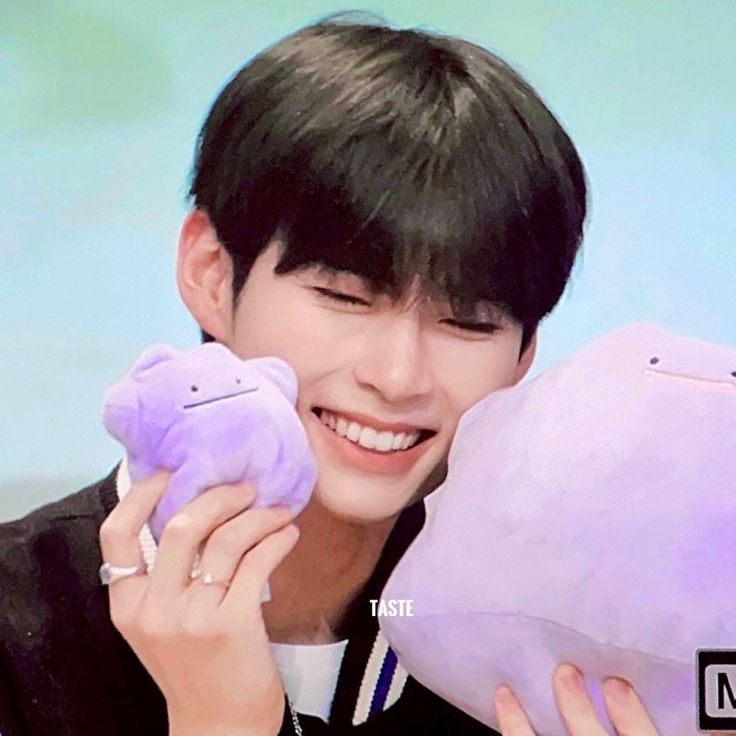 a man holding two stuffed animals in front of his face and smiling at the camera