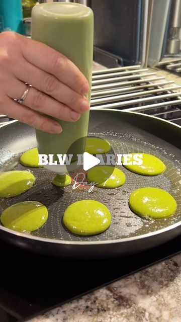 a person is holding a green beverage in a frying pan