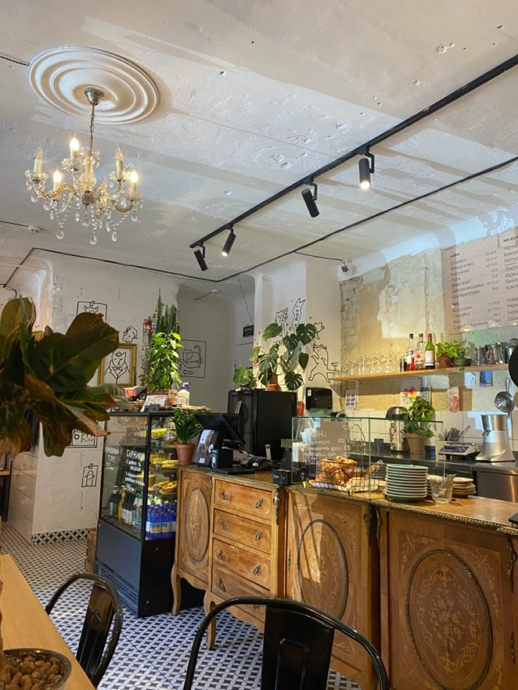 the inside of a restaurant with tables, chairs and potted plants hanging from the ceiling