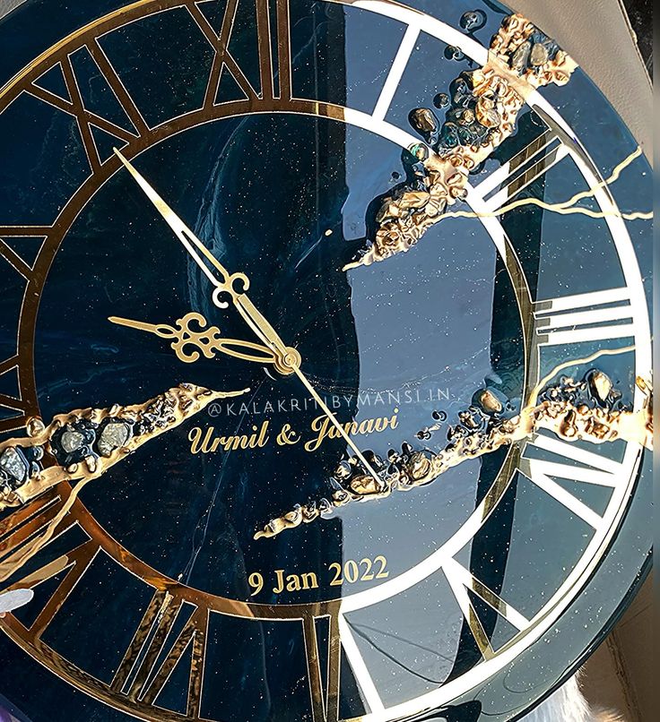 a blue and gold clock with roman numerals on it's face is shown