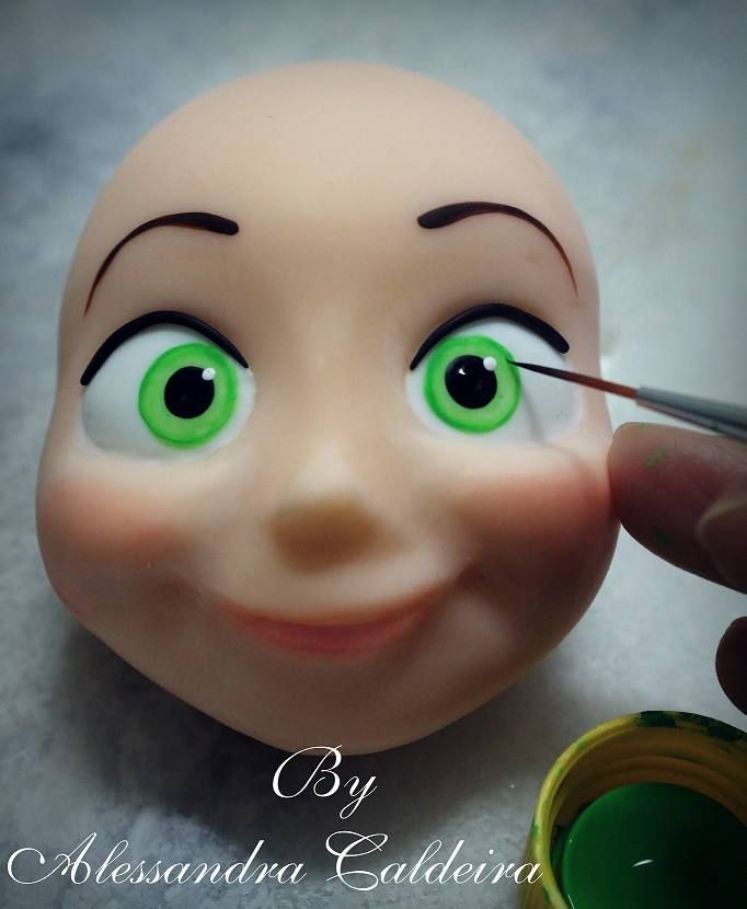 a doll head being painted with green eyes