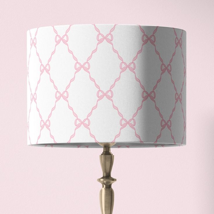 a pink and white lampshade with a gold metal base on a pink wall