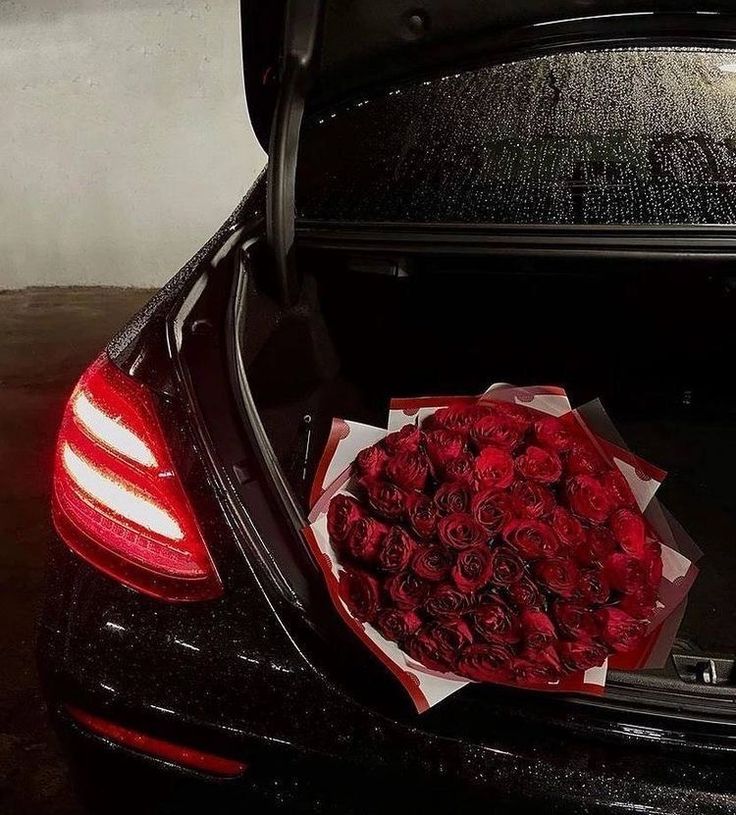 a bunch of red roses are in the trunk of a mercedes benz s - class