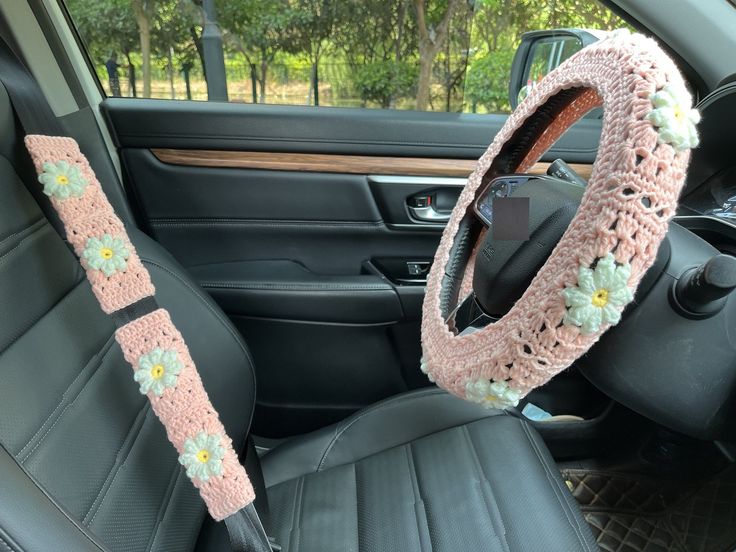 a crocheted steering wheel cover in the back seat of a car with flowers on it