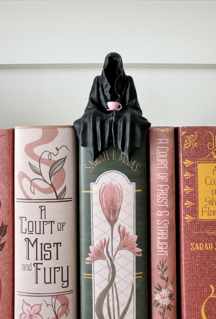 a row of books sitting on top of a shelf next to each other in front of a white wall